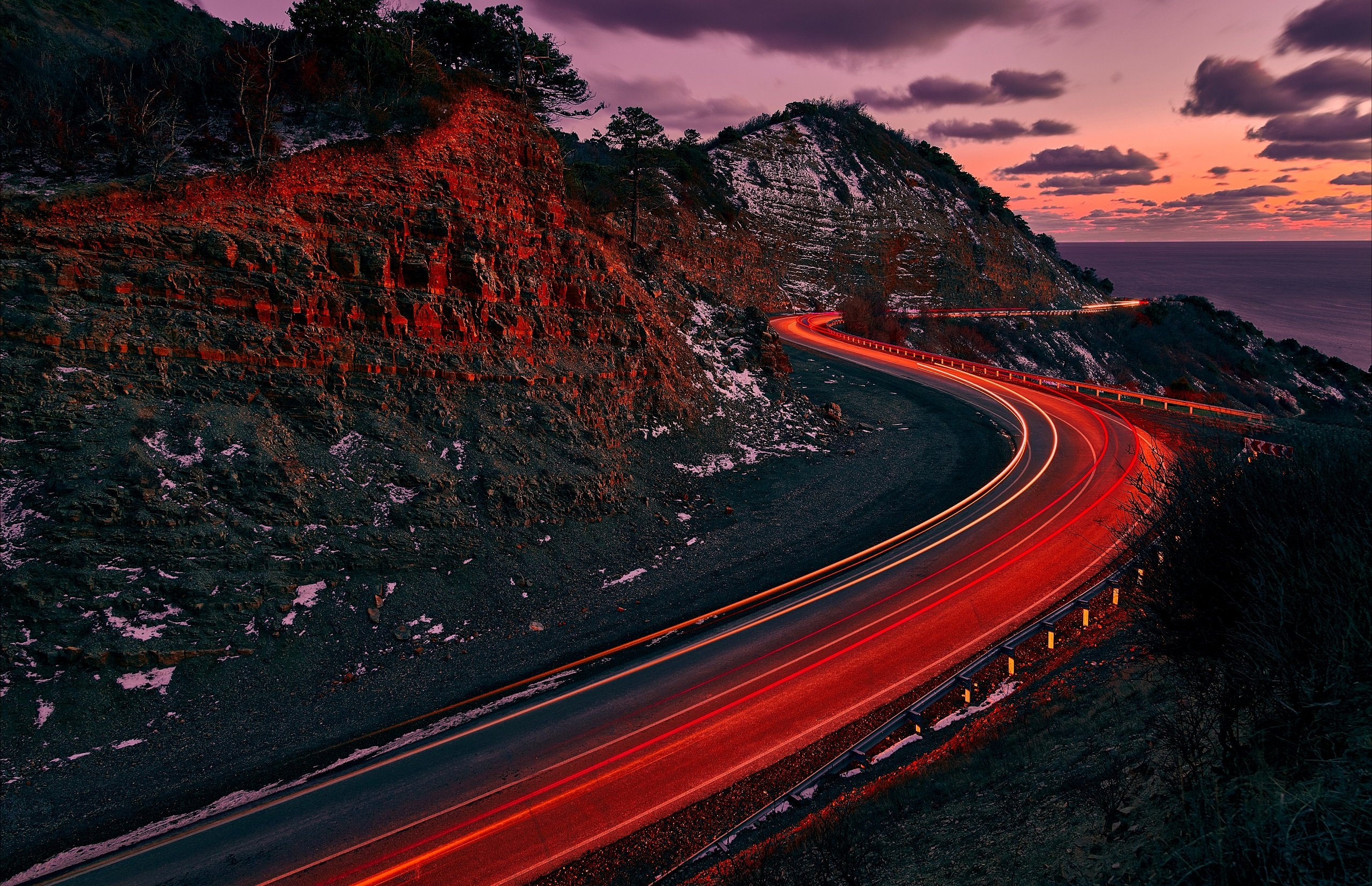 A winding road with red lights driving toward the future