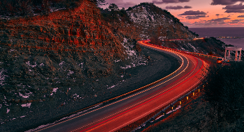 A winding road with red lights driving toward the future