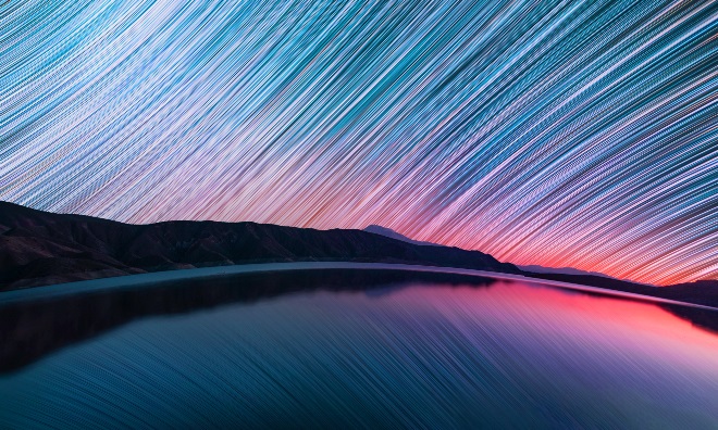 A watery landscape with a time lapse of the night sky