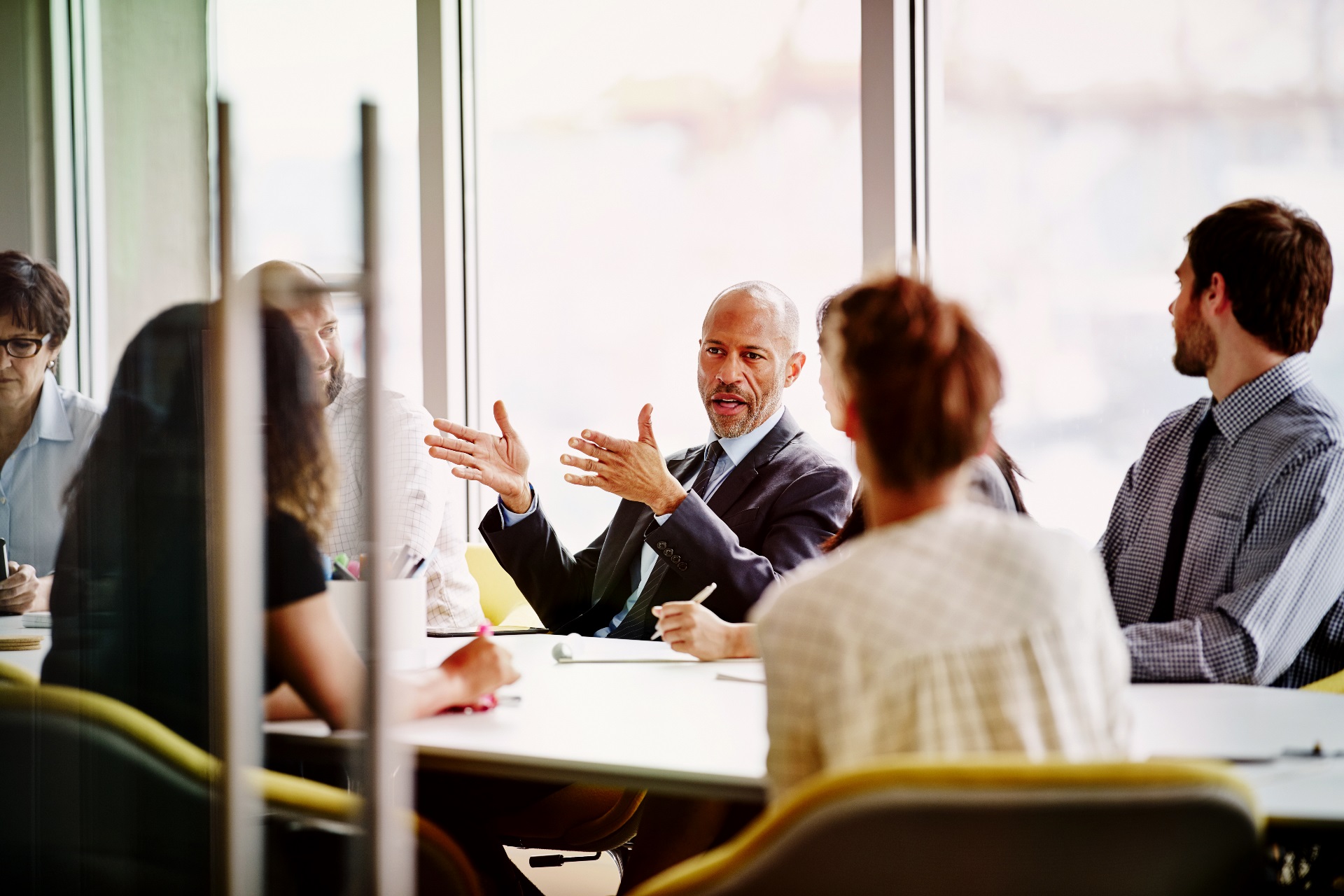 A team sits in a bright room around a table discussing business